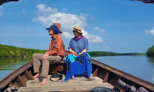 A couple sitting at the front of out traditional long-tail boat enjoying the views as we cruise though the Khao Lak mangroves